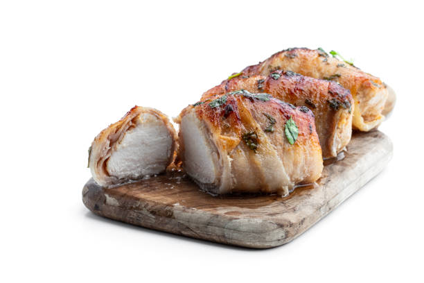Chicken breasts wrapped in bacon on wooden board isolated on white