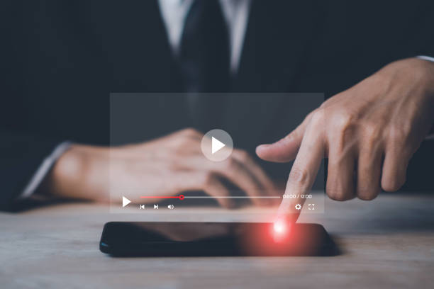 istock Video streaming online on smartphone with hologram. Man using smartphone on vacation. Social media and digital online concept. 1454806534