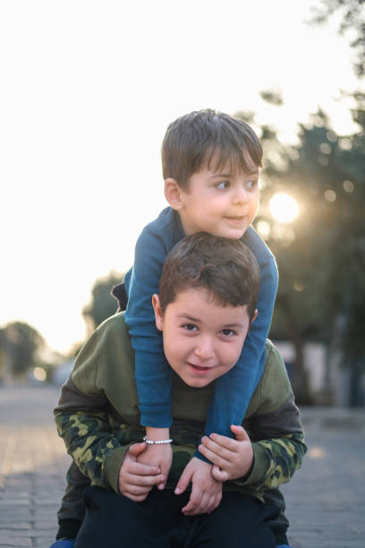 two children sitting and embracing on tall grass