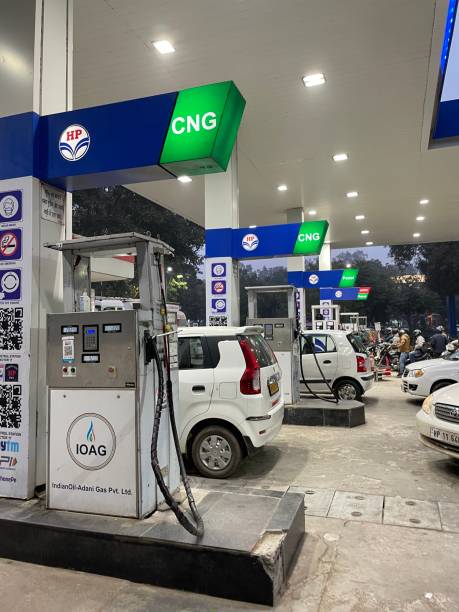 Close-up image of traffic on forecourt of gas filling station queuing for fuel pumps, motorists driving compressed natural gas (CNG) vehicles, cars and motorbikes, green fuel concept stock photo