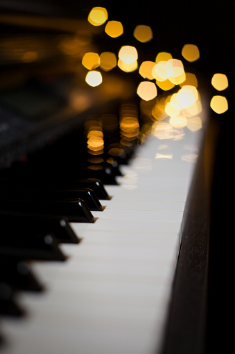 A closeup of piano keys with bokeh lights