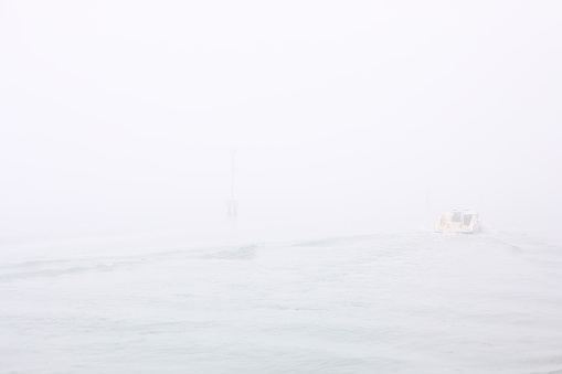 Daily life in Venice - Italy. Police motorboat in the distance on a foggy day in the Venetian lagoon.