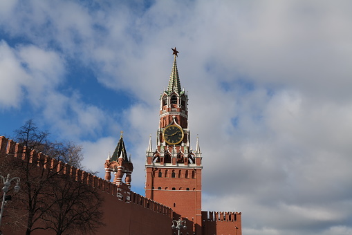 Spasskaya Tower of the Kremlin wall at the Red Square of Moscow. The sky is cloudy. We see the tower's clock and the red star on the top.