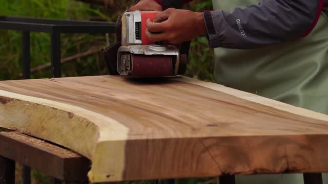 Hand of man sanding wood with orbital sander in a workshop
