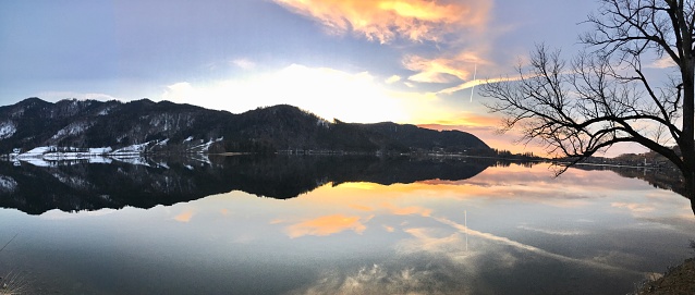 The Alps are reflected in Lake Schliersee at sunset in winter. Reflection of the mountains in the lake at sunset in winter.