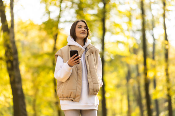 istock A happy woman in casual clothes smiles talks walks using a mobile phone technology alone in the autumn forest 1454830648