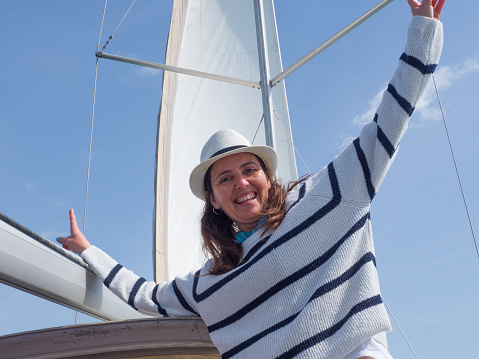 Woman with hat and striped marine sweater enjoying on board the boat with the concept of tranquility, on vacation