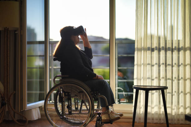 istock Woman in wheelchair using vr glasses at home 1454833108