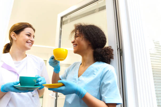 istock Two happy multi-ethnic female medical workers colleagues drinking coffee 1454833360