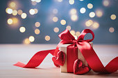 Gift box with bow ribbon and red hearts for Valentines day. Bokeh lights background.