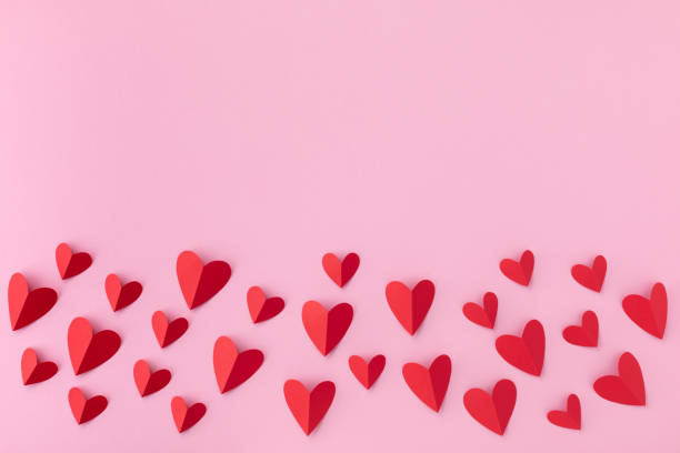 Border of various red hearts on pink background for Saint Valentine day greeting card or banner. stock photo