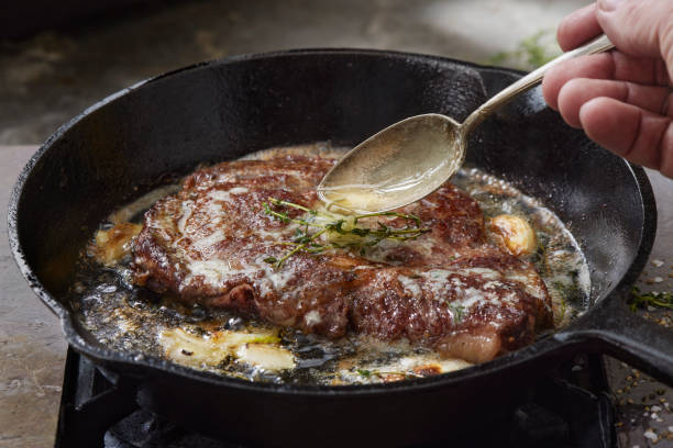 Pan Searing Beef Eye Rib Steak Pan Searing Beef Eye Rib Steak with Garlic, Butter and Thyme cooking with garlic stock pictures, royalty-free photos & images