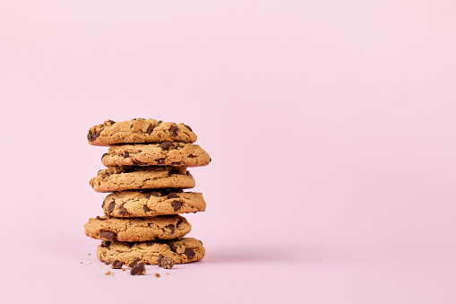 Pile of cookies isolated on pink background, with copy space