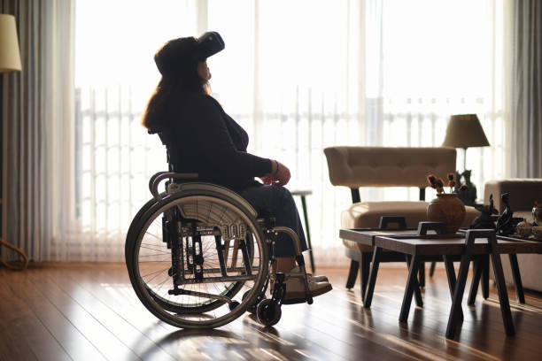 istock Woman in wheelchair using vr glasses at home 1454840237