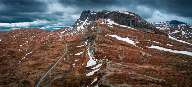 Landscape with road and mountain ridge in Jotunheimen National Park in Norway from above, dramatic dark cloudy sky