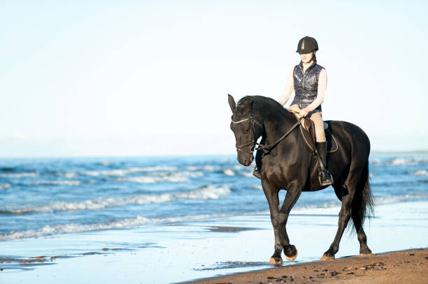 istock Young Lady riding horseback at wavy seaside/ocean coast 1454843006