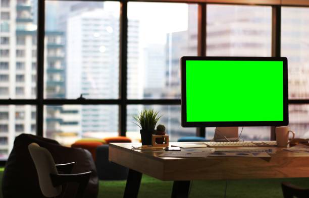 istock Wooden desk table office with big computer screen on windows and building background 1454846713