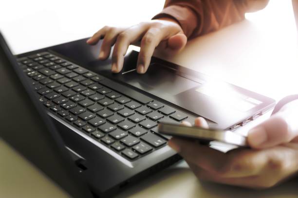 istock Hands using laptop and smartphone for online shopping with daytime soft light shining high contrast 1454850047