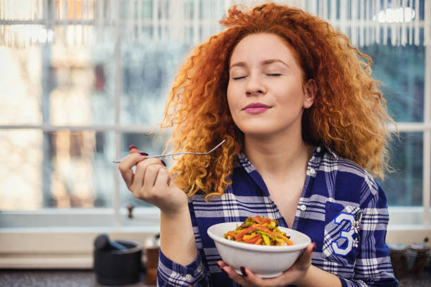 mujer comiendo una comida vegetariana saludable - tasting women eating expressing positivity fotografías e imágenes de stock