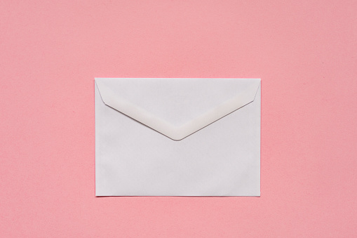 White paper envelope on pink background