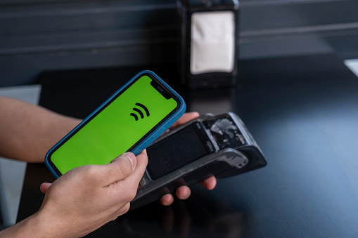 Man making contactless payment with phone at pizzeria