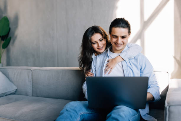 istock Young couple surfing on internet with laptop sitting on couch 1454854740