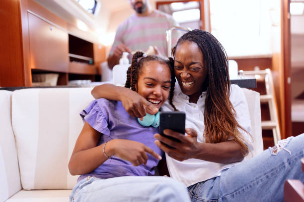 istock Family relaxing in yacht cabin using phone 1454857206