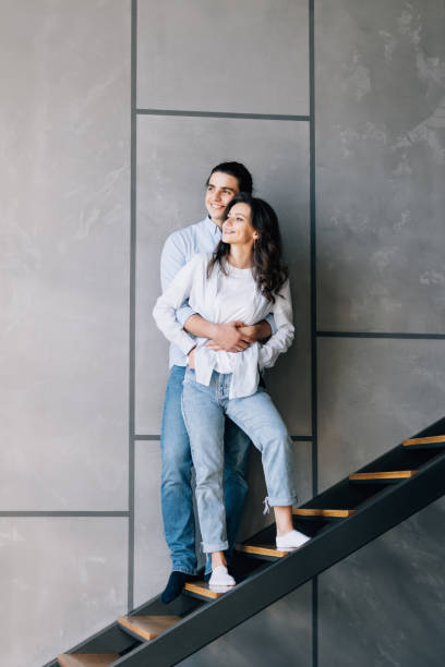 istock Handsome guy and his pretty lady sitting on stairs in modern interior room 1454857703
