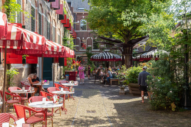 People enjoy the terrace in the courtyard of the former old orphanage in Gouda. Gouda, Netherlands, August 25, 2022; People enjoy the terrace in the courtyard of the former old orphanage in Gouda. gouda south holland stock pictures, royalty-free photos & images