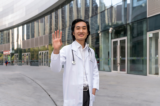 Male doctor waves at camera during web conference