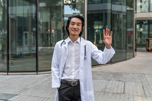 Friendly Male Doctor Waving to Welcome Patients
