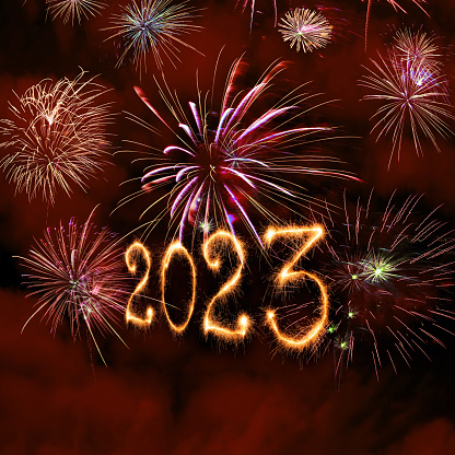 New Year fireworks and 2023 sign made of sparkler trace on a night sky background.