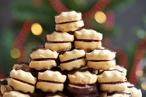 Closeup of a pile of homemade Christmas cookie filled with strawberry marmalade and dipped in chocolate