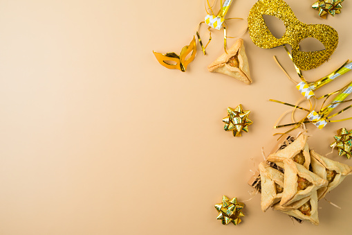 Jewish holiday Purim background with golden carnival mask and hamantaschen cookies. Top view, flat lay