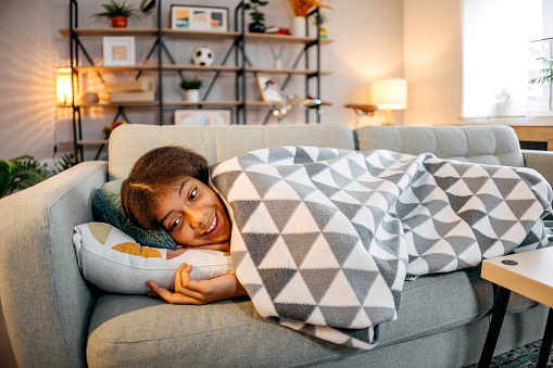 Girl resting on a sofa covered with blanket