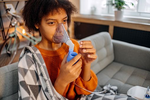 Girl using nebulizer during inhaling therapy
