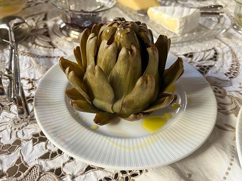 Boiled artichoke drizzled with olive oil on a luxurious table