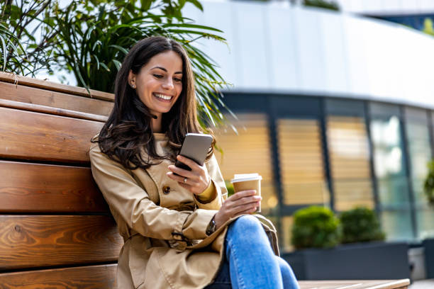 istock Woman sitting on bench and using smart phone 1454864517