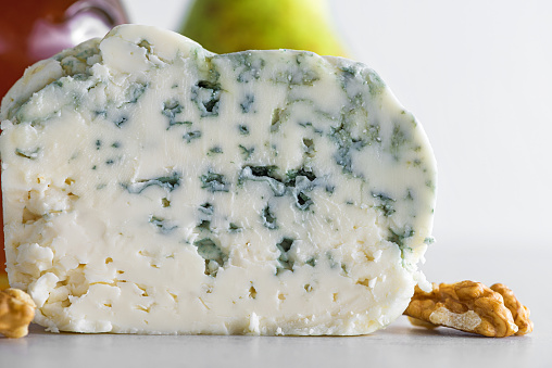 Delicious blue cheese dorblu or gorgonzola with pear and walnuts on white background. Close up. Tasty food