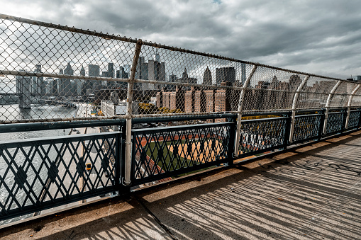The view of Manhattan and Chinatown from the Manhattan Bridge with its fence in the foreground