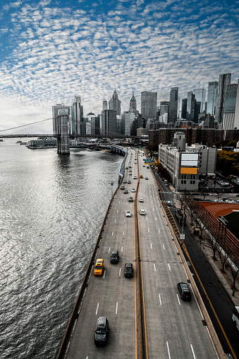 Lower Manhattan, highway and a part of the Brooklyn Bridge seen from the Manhattan bridge during a rush hour and an amazing sunset making a cloudy sky so impressive.
