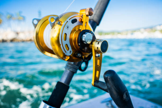 Closeup Ocean Fishing Reel on a Rod used for Catching Big Game Fish Such as Mahi Mahi, Tuna, Sailfish and Marlin on a Boat Near a Marina in Puerto Vallarta Mexico Closeup Ocean Fishing Reel on a Rod used for Catching Big Game Fish Such as Mahi Mahi, Tuna, Sailfish and Marlin on a Boat Near a Marina in Puerto Vallarta Mexico sea of cortes stock pictures, royalty-free photos & images