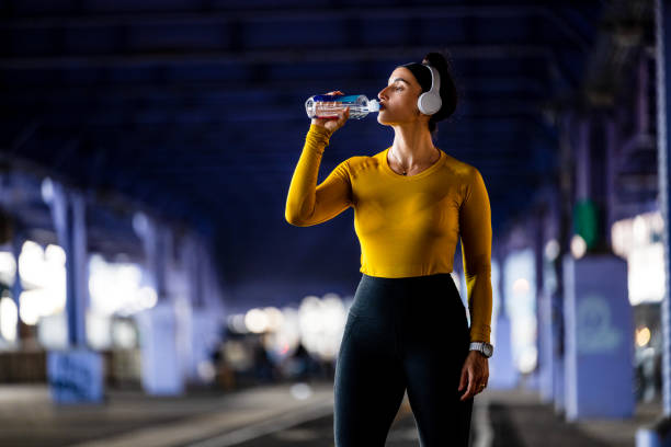 a woman drinking water during fitness activity in new york city - east river audio imagens e fotografias de stock