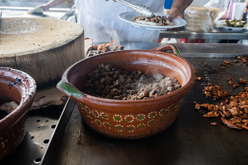 Street Taco Stand Kitchen Scene Pot of Carne Asada Warming on a Griddle as Cook Assembles Tacos in the Background in Mazatlán, Sinaloa, Mexico