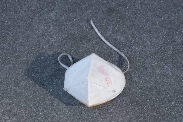 istock Used protective mask on an asphalt ground 1454872464