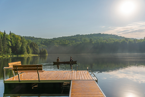 Couple canoeing on a lake of the Laurentians,  Quebec, during a sunrise of summer.