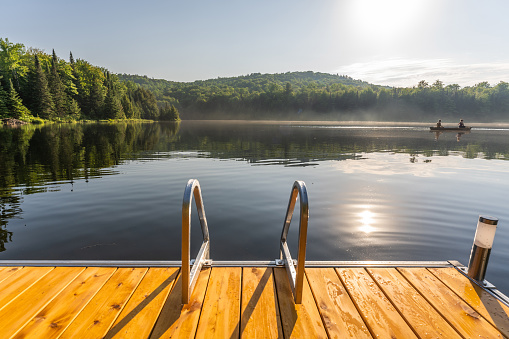 Couple canoeing on a lake of the Laurentians,  Quebec, during a sunrise of summer.