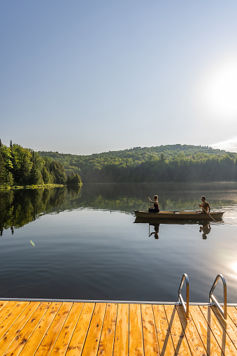 Couple canoeing on a lake of the Laurentians,  Quebec, during a sunrise of summer.