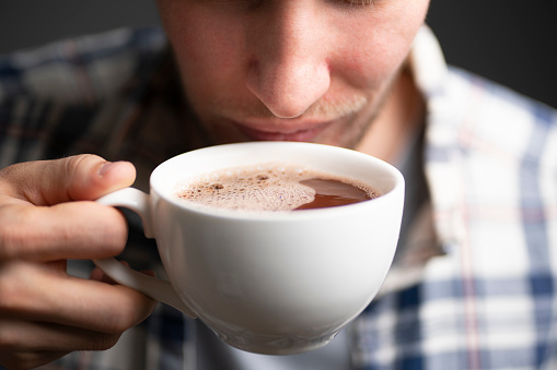 person holding white cup of coffee and drink it on a winter cold day