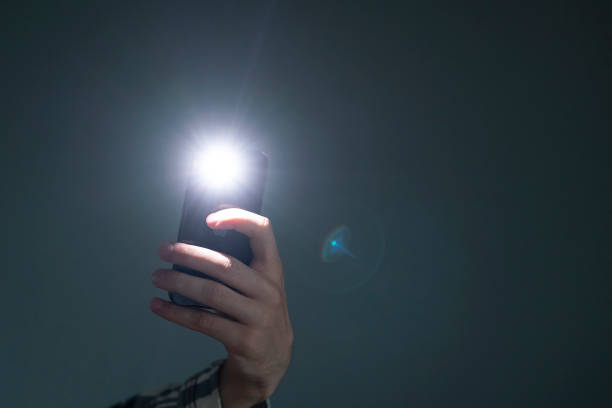 hand holding a smartphone used as a torched, flashlight of mobile phone in the dark hand holding a smartphone used as a torched, flashlight of mobile phone in the dark electric torch stock pictures, royalty-free photos & images